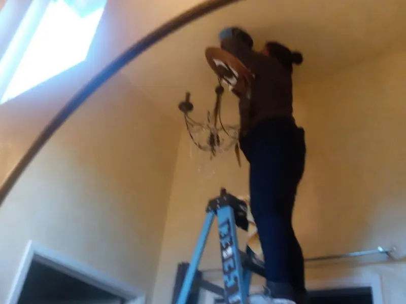 Electrician installing a chandelier in a Terrell residence